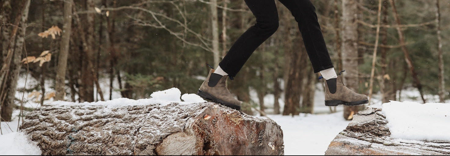 Blundstone boot wearing Person walking on a log in a snowy forest